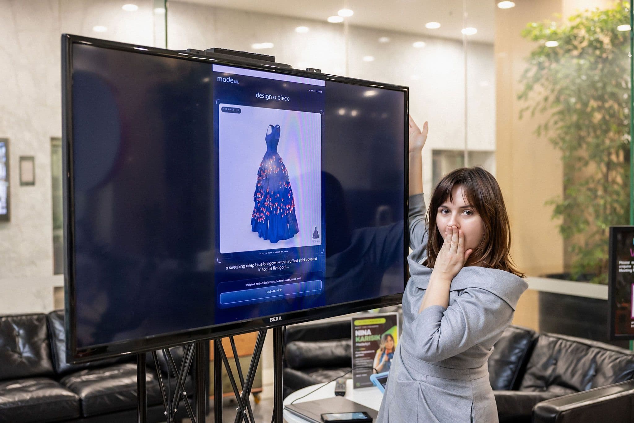 The Spacecubed lobby screen showing a deep-blue ballgown turning in 3D in the MadeApt studio, with MadeApt’s founder beside it