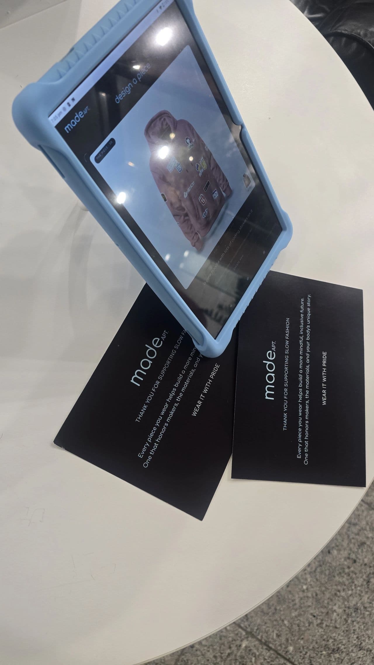 The studio tablet showing a pink sticker hoodie in 3D, next to MadeApt thank-you cards