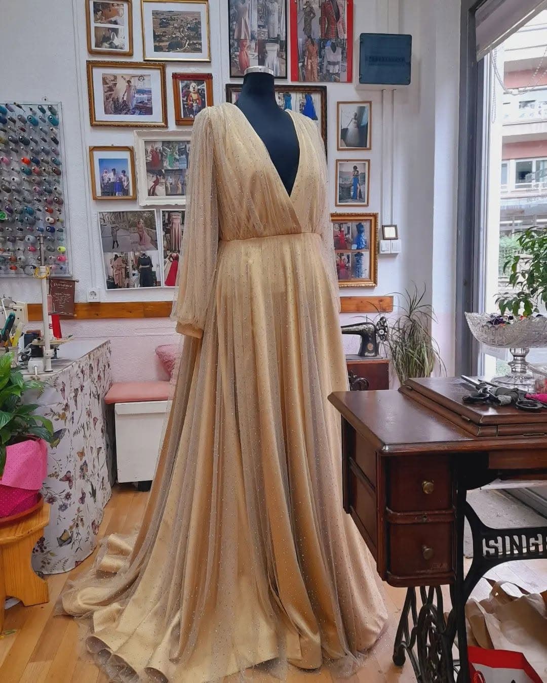 A custom gold occasion gown with sheer beaded sleeves and a full train, in the tailor's studio