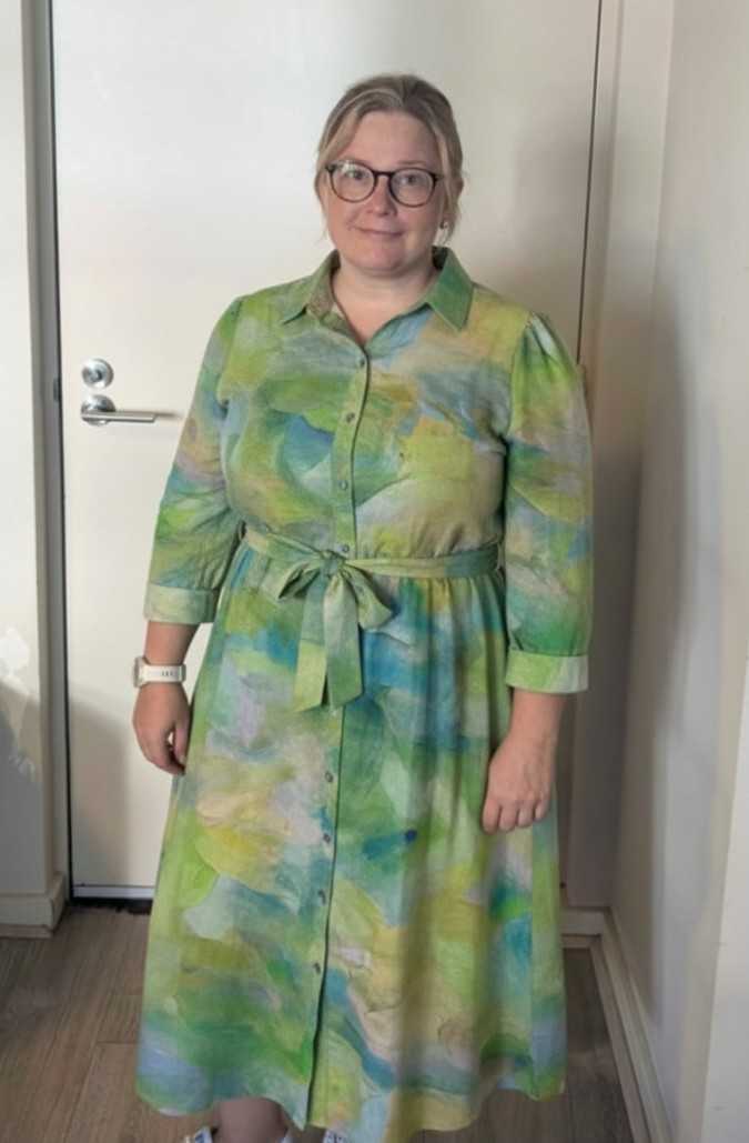 Erin at home in a preview of the shirt dress design, standing by a door