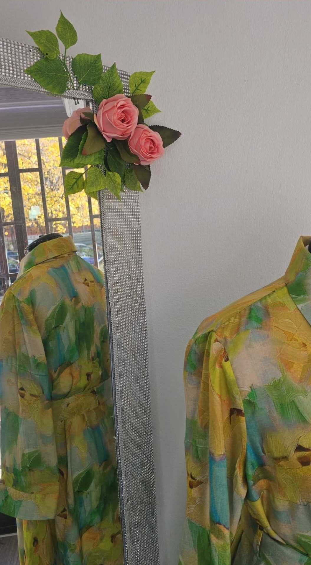 The finished silk shirt dress on a dress form in the Sarajevo workroom, reflected in a mirror framed with crystals and pink roses
