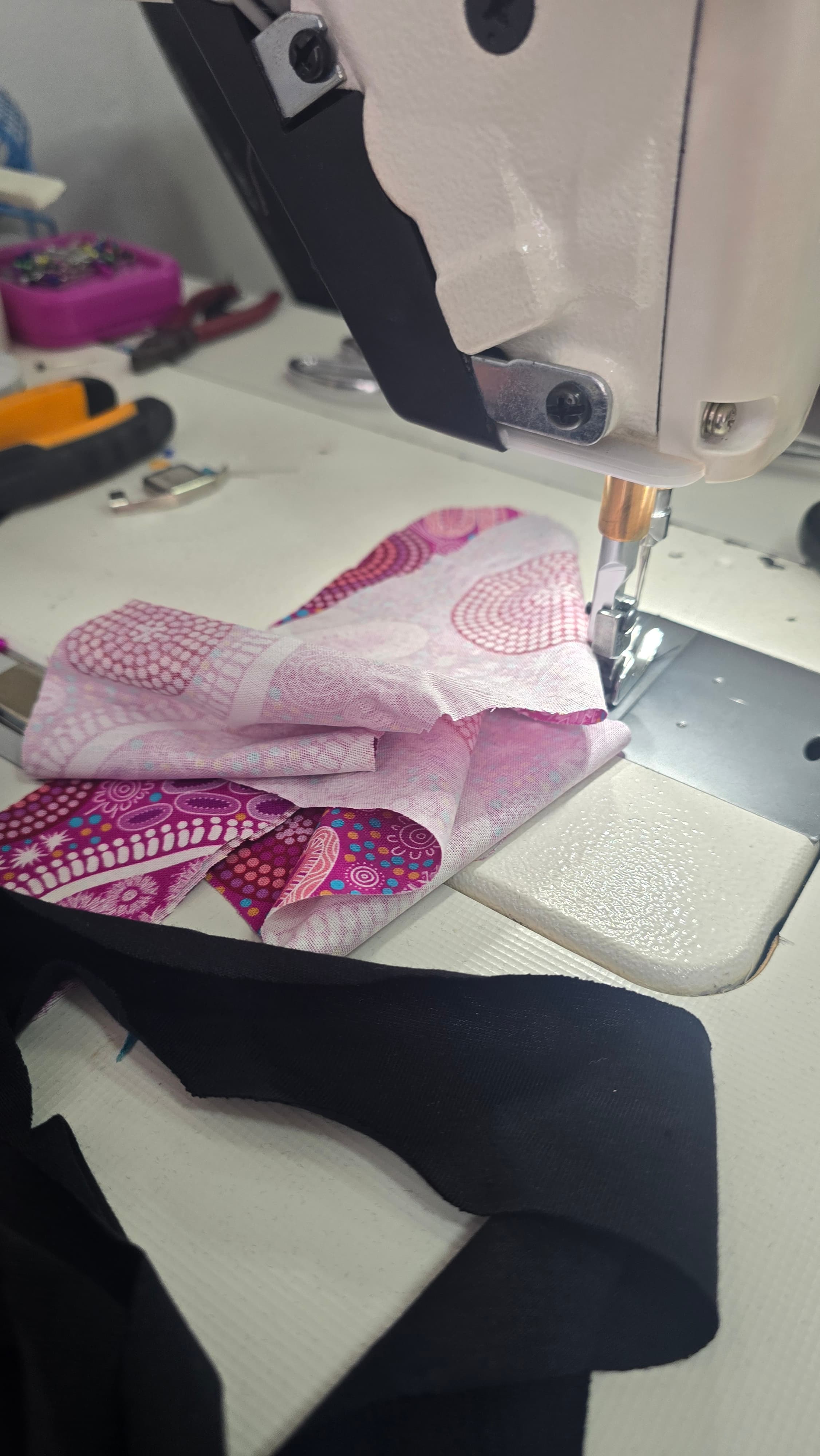 Printed fabric under the foot of a sewing machine, mid-construction