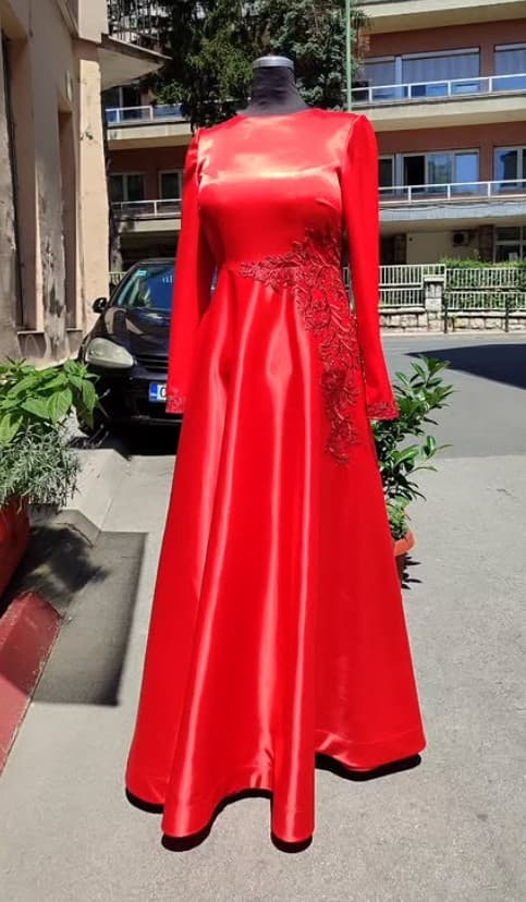 A custom red satin long-sleeve modest gown with beaded appliqué along the bodice