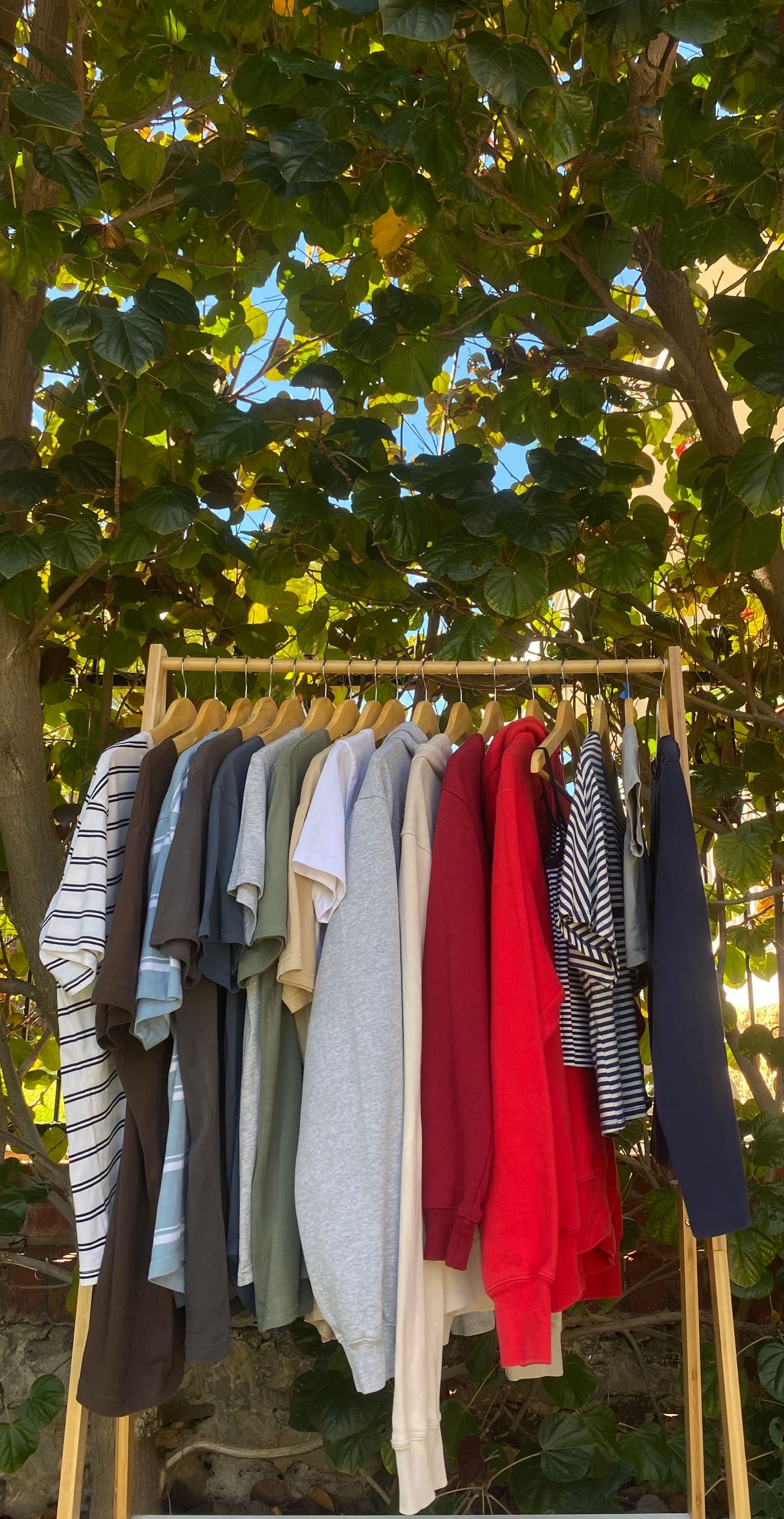 Rack of second-hand tees and sweatshirts under a tree