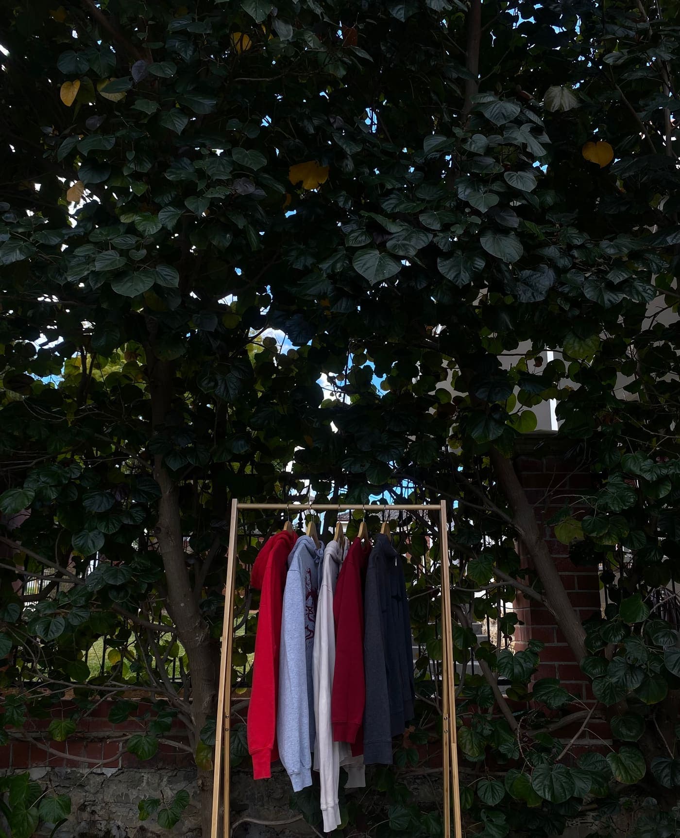 Hooded sweatshirts on a wooden rack in the shade
