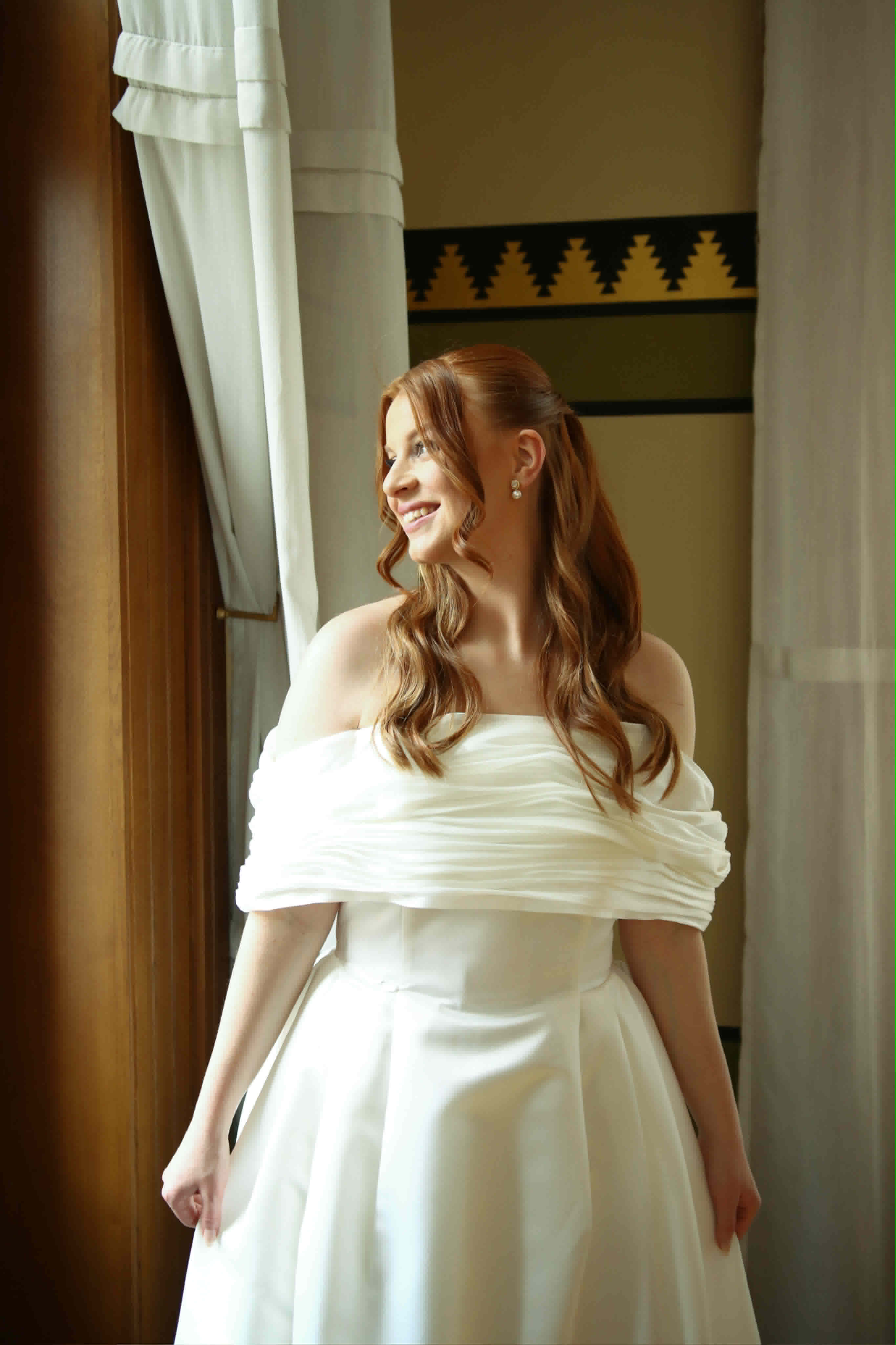 A bride in a custom off-the-shoulder draped wedding gown