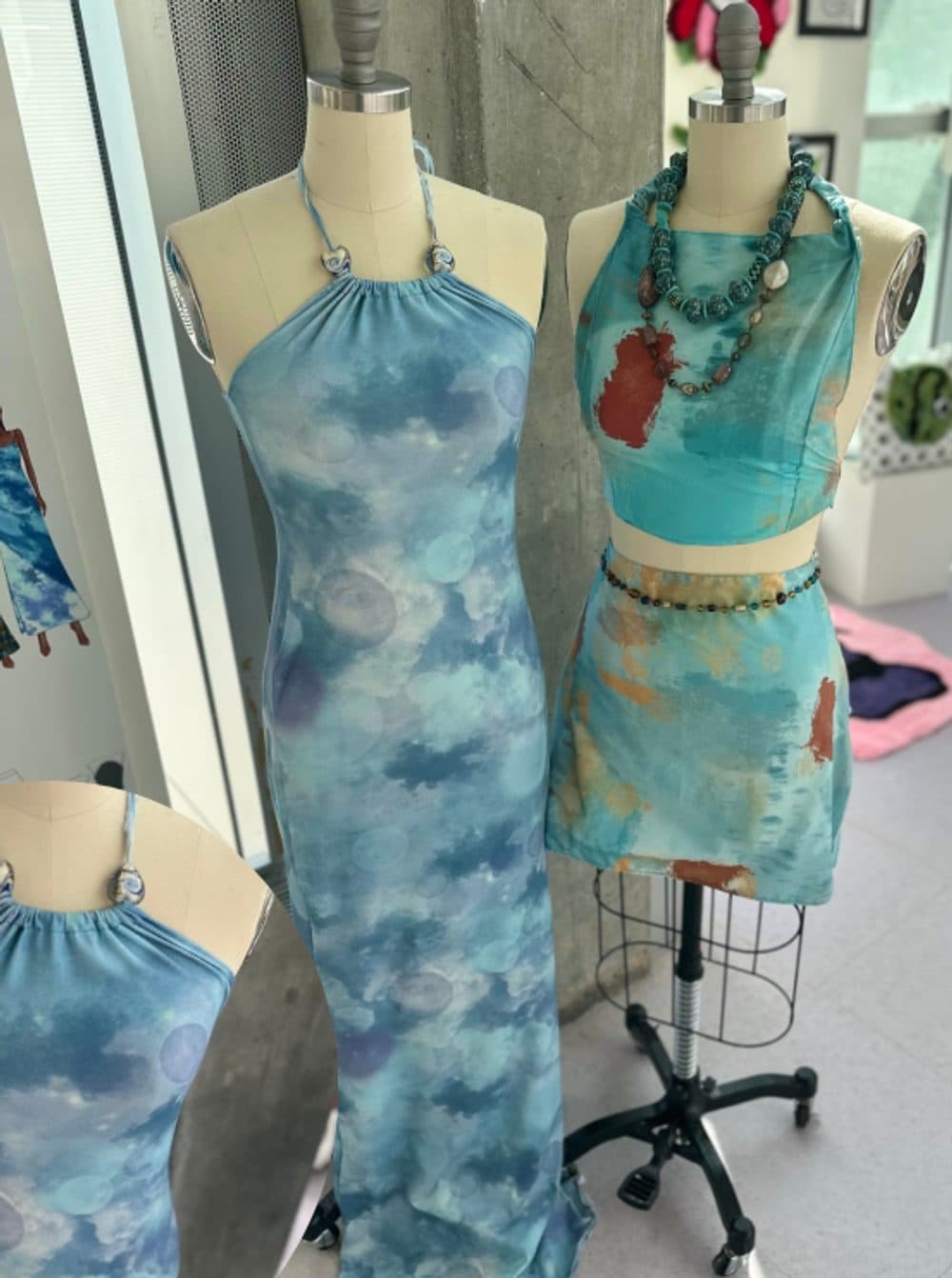 A halter-neck column dress and a halter top with mini skirt in blue and turquoise watercolour prints, on dress forms
