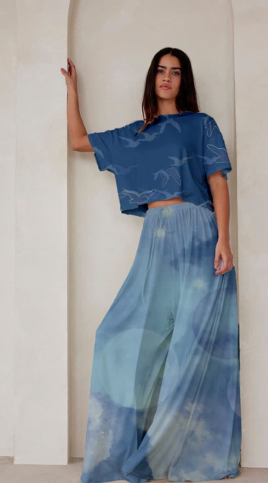 Digital mockup of a cropped tee printed with birds in flight over wide-leg trousers in a soft blue print
