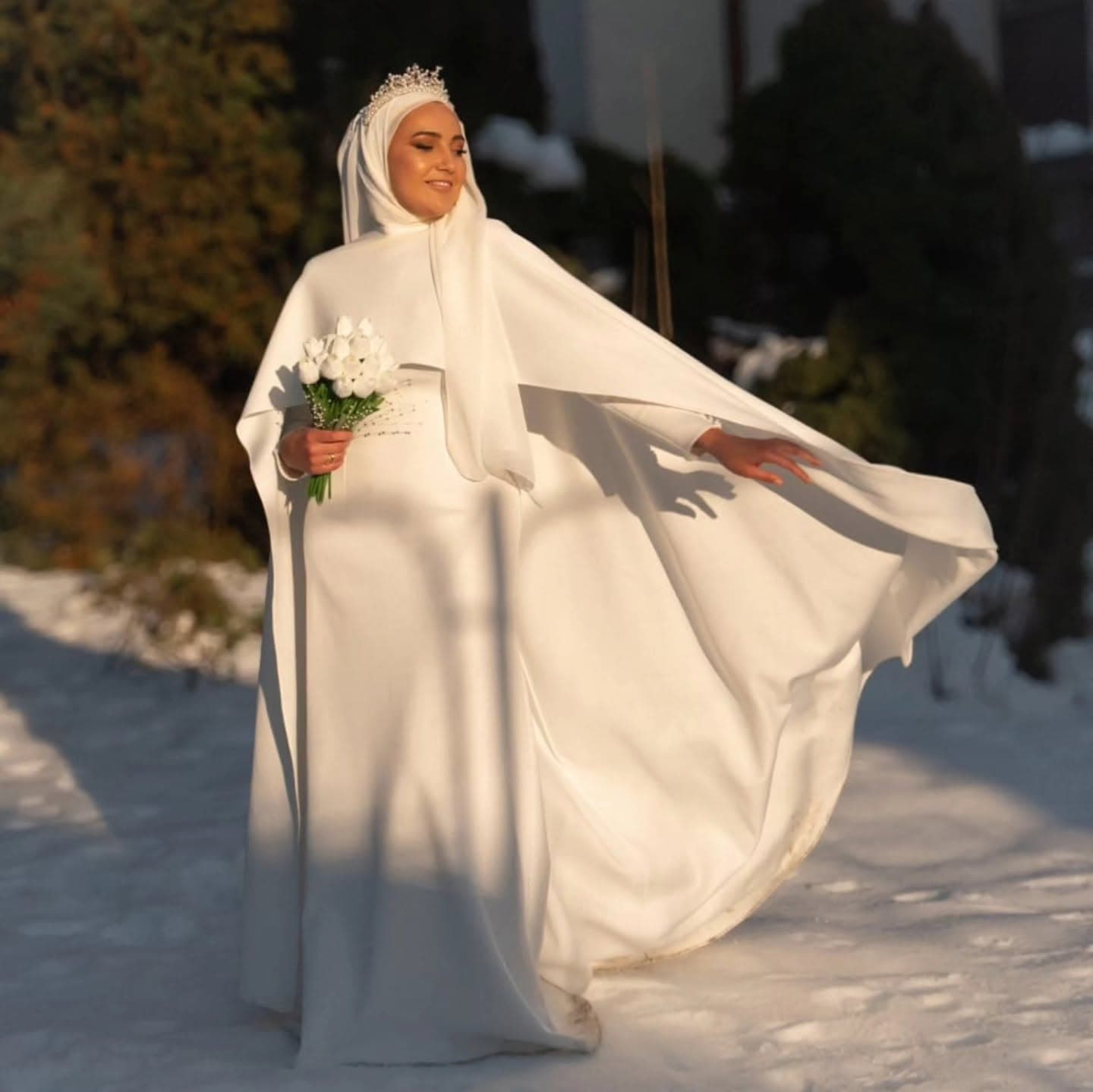 A bride in a custom modest wedding gown with long sleeves, cape and hijab styling, sewn to her measurements