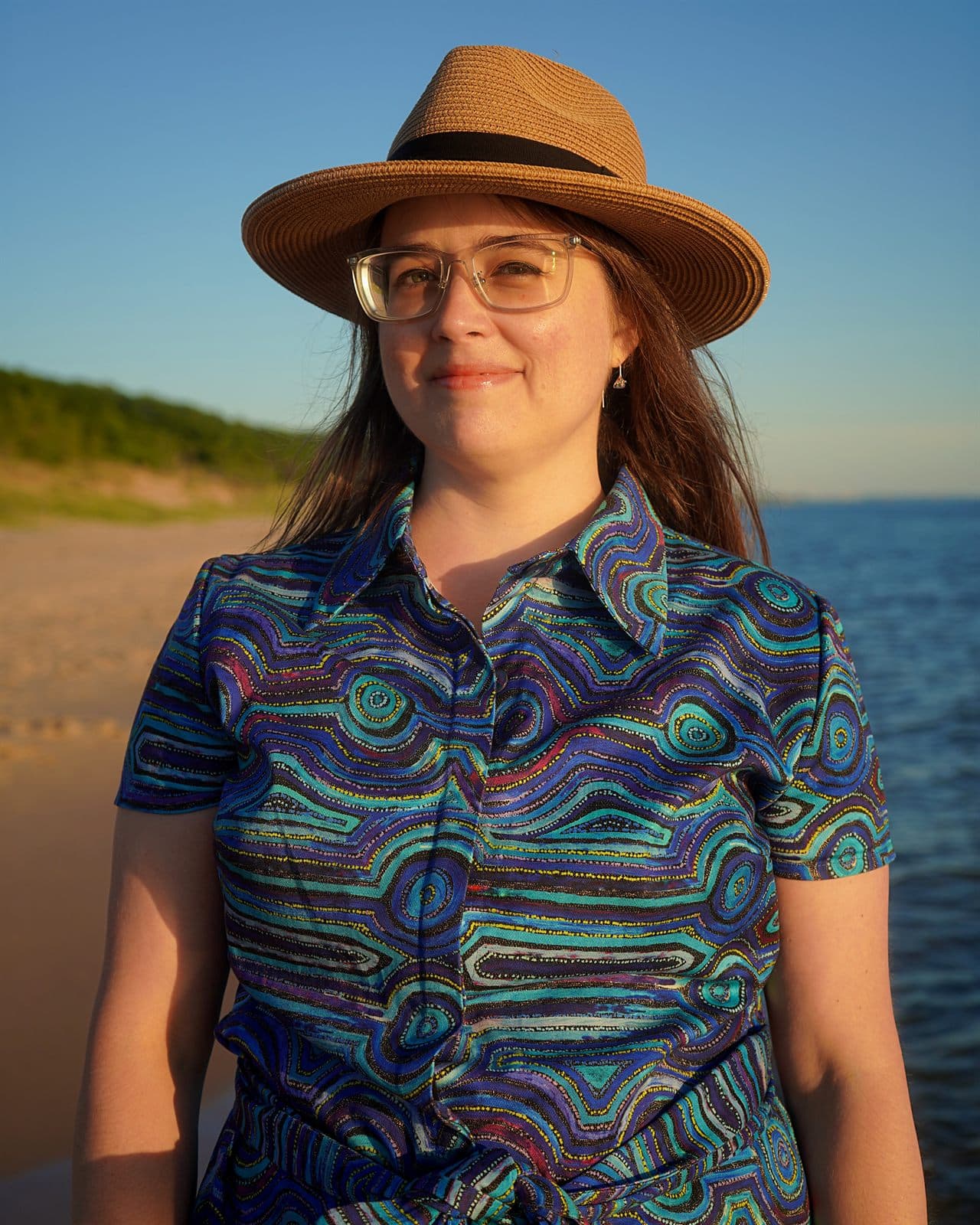 Mary wearing her custom Emu Dreaming shirt dress by the beach.
