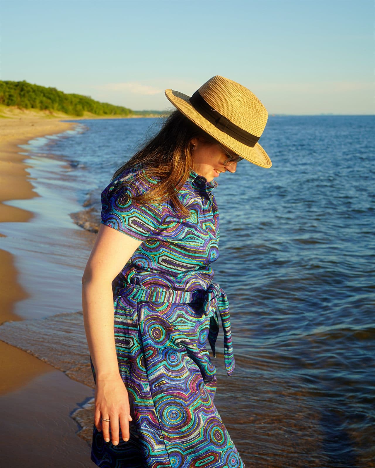 Mary wearing a blue Emu Dreaming cotton shirt dress with a waist tie on the beach.
