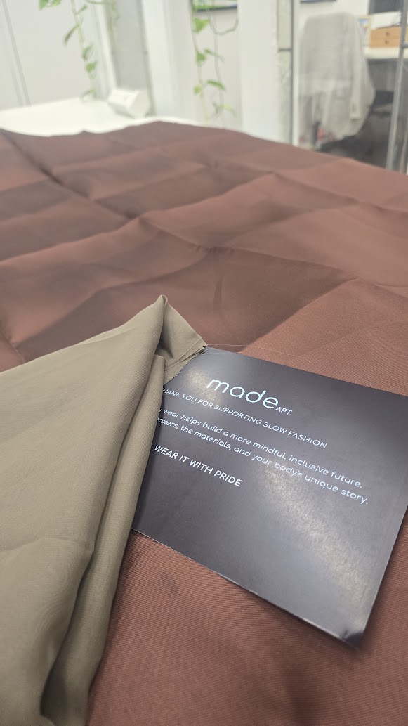 Approved fabric and lining laid out on the cutting table with a MadeApt card
