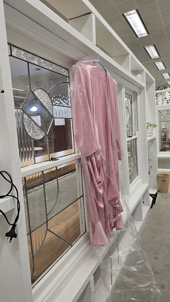 A finished pink garment hanging in a protective bag, ready for final review